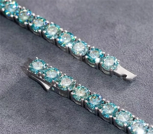 Detailed close-up of teal moissanite tennis bracelet with silver clasp and high fire color