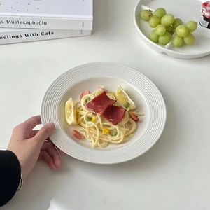 Close-up of creamy pasta with ham and lemon served in a white ceramic wide-rim bowl