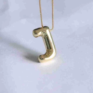 Macro detail of puffy letter J pendant in gold finish with a polished box chain necklace
