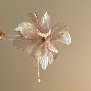 Detailed view of champagne floral hair pin with elegant pearl tassel on gold metal fork
