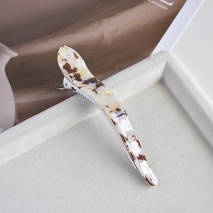 Detailed close-up of large acetate claw clip with tortoise pattern on beige velvet tray