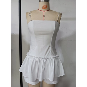 Detail of white spaghetti strap dress featuring ruffled hem and minimalist bodice design