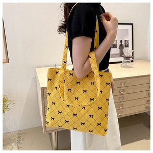 Dettaglio macro della borsa tote in velluto giallo con motivi a fiocco nero e trapuntata
