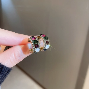 Detailed view of luxury C-shaped gold earrings with colorful zircon and micro-pave stones