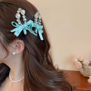 Détail de barrettes nœud bleu avec strass portées sur cheveux longs pour un look chic