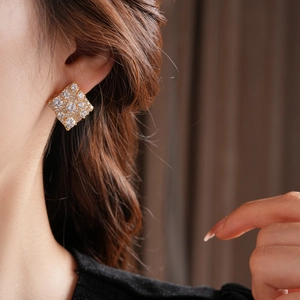 Gros plan sur les boucles d'oreilles carrées dorées serties de zircons étincelants