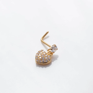 Detail shot of golden L-shaped nose stud with zircon heart pendant on white background