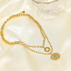 Detail of double-layered gold titanium necklace with star and turquoise stone pendant