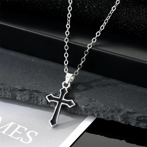 Punk style cross pendant necklace with black enamel and silver chain on stone background