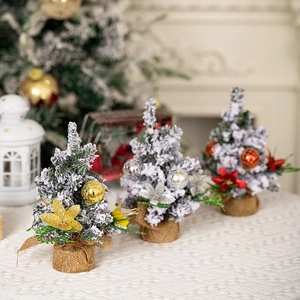 Close-up of mini snowy Christmas trees with colorful ornaments and burlap base