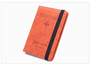 Detail of vintage orange leather passport holder with elastic band and airplane embossing