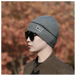 Detailed close-up of grey ribbed knit beanie texture with a minimalist fashion patch