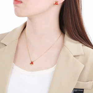 Festive red Christmas bell necklace and stud earrings set worn by a fashion model