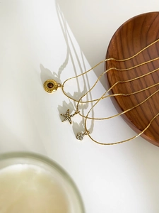 Detailed shot of gold plated necklaces with starfish, eye and flower charms on wood