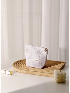 Pink swan jacquard cosmetic bag with gold zipper and minimalist brand label on wooden stand