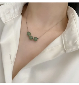 Detailed view of triple green jade beads pendant necklace on a minimalist silver chain