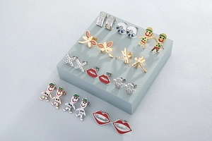 Detail view of assorted stainless steel stud earrings with dragonfly and palm motifs