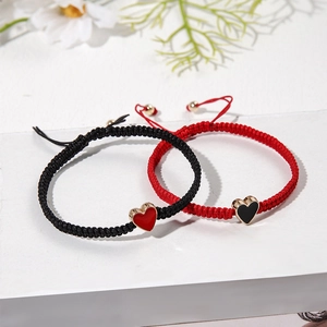 Detail of adjustable couple bracelets with heart pendants on a white geometric surface