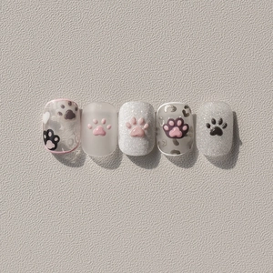 Close-up of 3D embossed cat paw nail stickers with pink and black hand-painted patterns