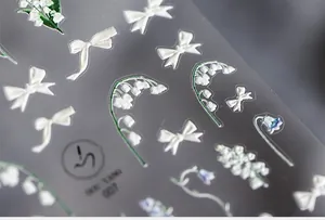 Détail macro de stickers ongles 3D avec nœuds blancs et fleurs de muguet élégantes