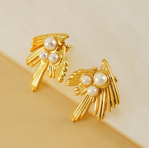 Close-up of vintage 18K gold-plated swallow earrings with three pearls and sunburst texture