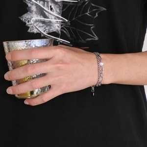 Detail of silver double-layer bracelet with pearls on wrist against black shirt