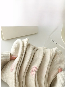 Dettaglio di calze in maglia crema con gommini antiscivolo rosa sulla suola