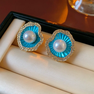 Macro d'une boucle d'oreille coquillage avec émail bleu, perle blanche et cristaux