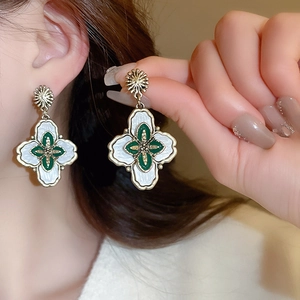 Vue macro des boucles d'oreilles fleurs vintage avec finition dorée et émail blanc