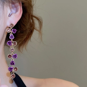 Close-up of sparkling flower pendant tassel earrings with purple roses on a model