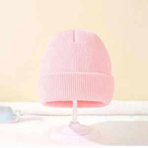 Close-up of pink knitted beanie for kids on a stand with soft winter texture details