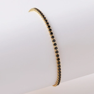 Detail eines verstellbaren Tennisarmbandes mit schwarzen Edelsteinen in Goldfassung