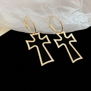 Close-up of gold gothic cross earrings with black inlay and intricate woven texture