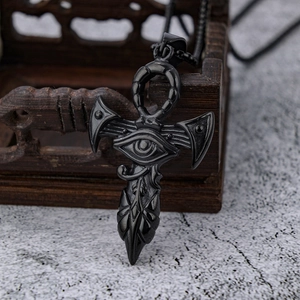 Detailed shot of a black stainless steel Eye of Horus Ankh cross pendant on a wooden box