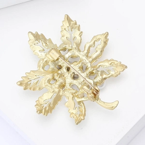 Detailed back view of a golden leaf brooch showing the secure pin fastener and metal texture