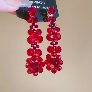 Detail of red tiered crystal bead tassel earrings with faceted flower cluster droplets
