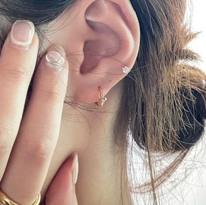 Close-up of a model wearing gold knotted hoop earrings and a minimal matching ring