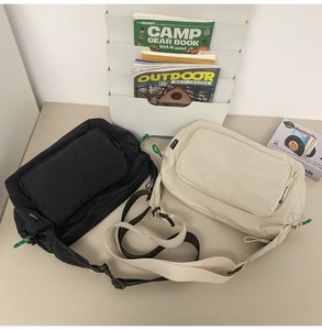 Still life display of black and cream nylon messenger bags with adjustable straps