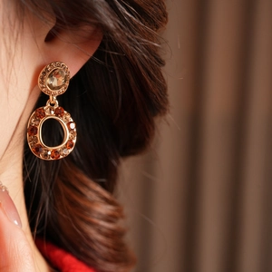 Macro view of vintage gold-tone earrings with amber and champagne crystals on model