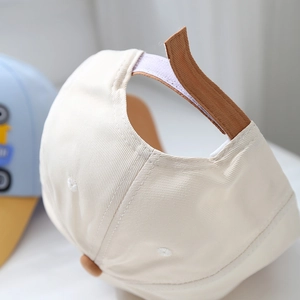 Close-up detail of beige cotton toddler cap with adjustable brown velcro strap fastener