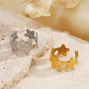 Anelli a fiore regolabili placcati oro 18K e argento su base di marmo beige