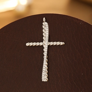 Detail of silver cross pendant with micro-paved cubic zirconia and rope texture design