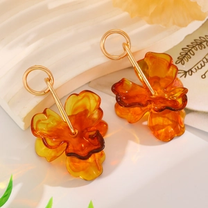 Detail view of amber resin flower earrings with gold circular metal drop accents