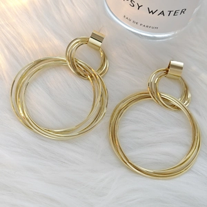 Close-up of golden multi-layer interlocking metal hoop earrings on white faux fur background