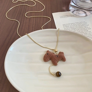 Detailed macro view of a flocked pony pendant with natural tiger eye stone on a gold chain
