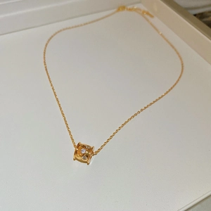 Detail of 18k gold plated flower lock pendant with crystals on a white jewelry tray