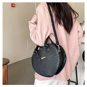 Sac à main coeur noir à motif crocodile et bandoulière porté par un mannequin