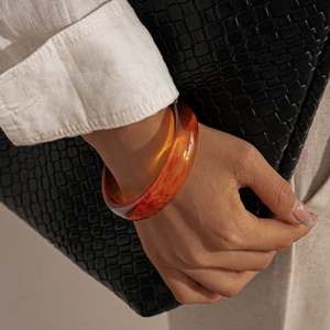 Close-up of wide amber resin bangle showing detailed red-brown marbled texture on wrist