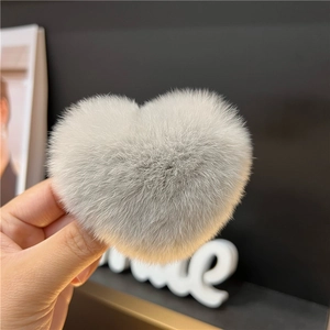 Close-up of a soft grey heart-shaped faux rabbit fur hair claw clip held in hand