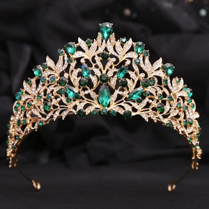 Detail of golden baroque crown with green emerald crystals and floral metal patterns